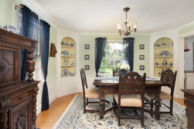 41 Northridge Ave, Torrington, CT 06790 - dining space featuring built in shelves, a chandelier, light wood-style flooring, a textured ceiling, and crown molding
