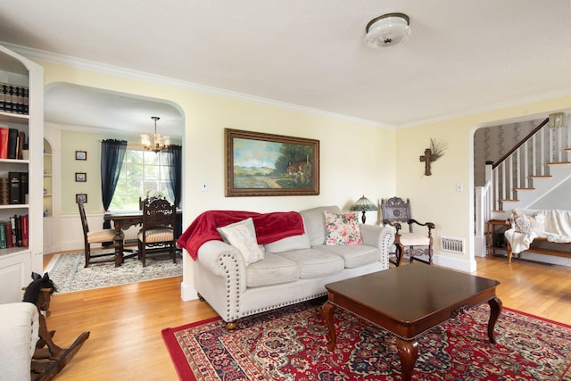 41 Northridge Ave, Torrington, CT 06790 - living room featuring crown molding, a chandelier, stairway, light wood-type flooring, and arched walkways