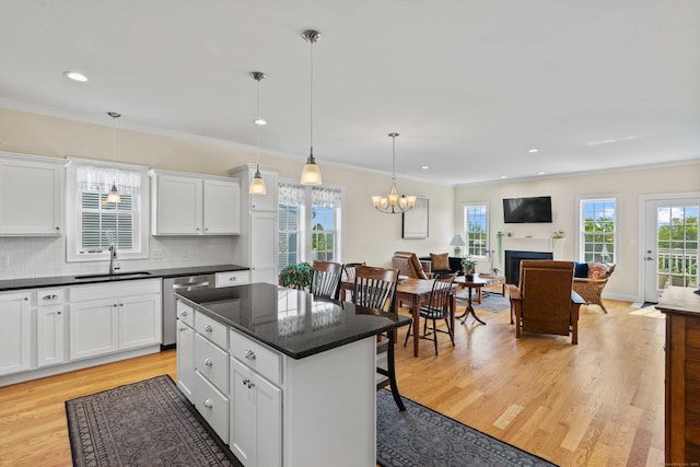 115 Webster Ln Unit 115, Middletown, CT 06457 - kitchen with stainless steel dishwasher, dark countertops, light wood finished floors, a fireplace, and white cabinets