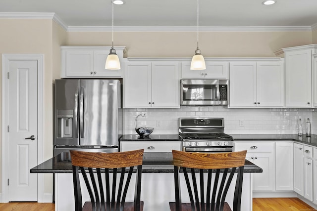 115 Webster Ln Unit 115, Middletown, CT 06457 - kitchen featuring appliances with stainless steel finishes, dark countertops, white cabinetry, a kitchen island, and crown molding