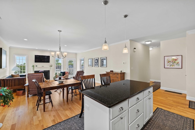 115 Webster Ln Unit 115, Middletown, CT 06457 - kitchen with open floor plan, a fireplace, light wood-style floors, white cabinets, and decorative light fixtures