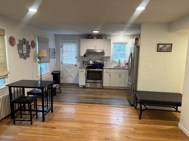 24 N Forest Cir, West Haven, CT 06516 - kitchen with stainless steel appliances, white cabinetry, light wood-type flooring, and under cabinet range hood