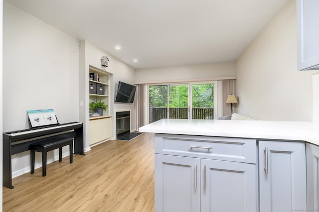 51 Old Kings Hwy Unit 5, Greenwich, CT 06897 - kitchen with a peninsula, a glass covered fireplace, light wood-style floors, light countertops, and recessed lighting