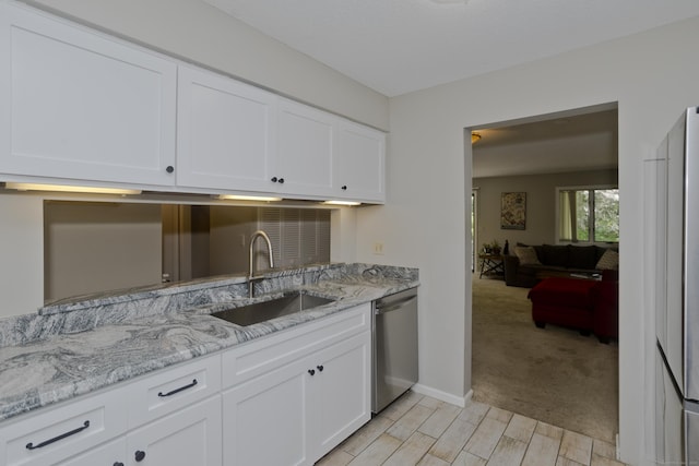 94 The Laurels Unit 94, Enfield, CT 06082 - kitchen with stainless steel dishwasher, white cabinetry, light stone countertops, and light wood-style flooring