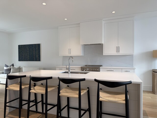 785 Post Rd E Unit 202, Westport, CT 06880 - kitchen with light countertops, white cabinetry, light wood finished floors, recessed lighting, and a breakfast bar