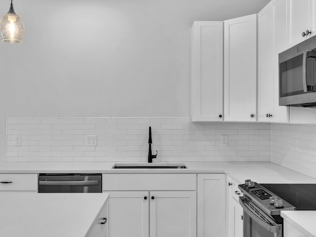 138 Boston Post Rd Unit 15, East Lyme, CT 06333 - kitchen featuring appliances with stainless steel finishes, tasteful backsplash, white cabinetry, light countertops, and decorative light fixtures