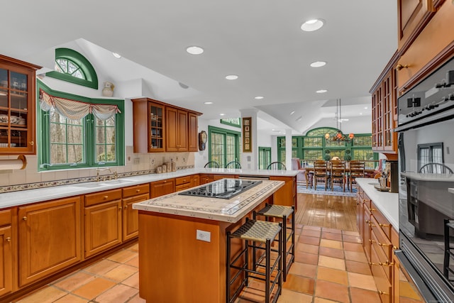 604 W Lake Ave, Guilford, CT 06437 - kitchen with black electric stovetop, a peninsula, light countertops, a kitchen breakfast bar, and a center island