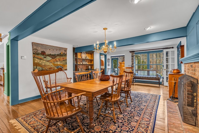 604 W Lake Ave, Guilford, CT 06437 - dining room with light wood finished floors, a chandelier, and a brick fireplace