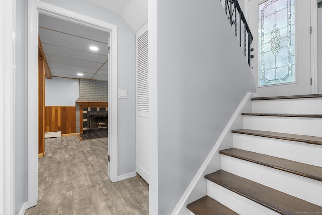 32 Cullen Ave, West Haven, CT 06516 - stairway featuring a baseboard heating unit, wood finished floors, recessed lighting, a brick fireplace, and wooden walls