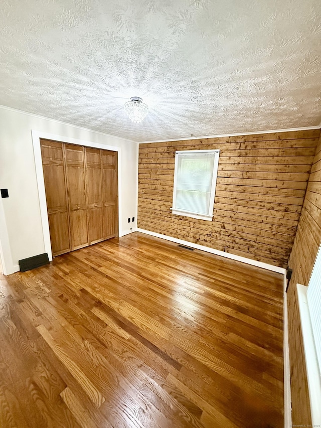 3951 S St, Coventry, CT 06238 - unfurnished bedroom featuring wood finished floors, a textured ceiling, a closet, and wooden walls