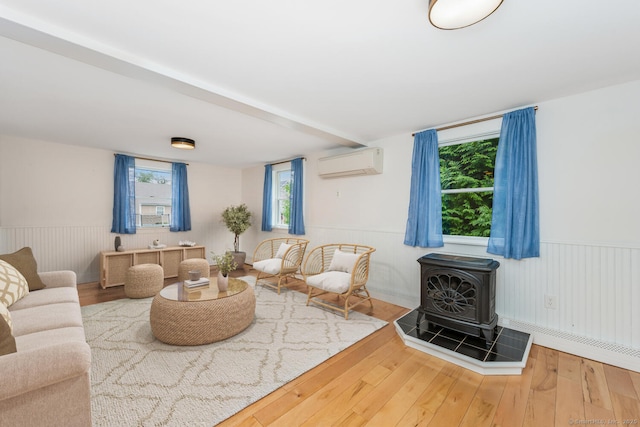 10 Sable St, Norwalk, CT 06854 - living area with a wall unit AC, a wood stove, wood finished floors, and a wainscoted wall