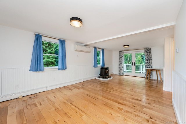 10 Sable St, Norwalk, CT 06854 - unfurnished living room with a wall mounted air conditioner, a wood stove, french doors, hardwood / wood-style floors, and wainscoting