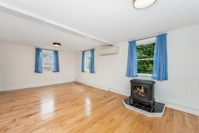 10 Sable St, Norwalk, CT 06854 - unfurnished living room with a wall mounted AC, a wood stove, wood finished floors, and wainscoting