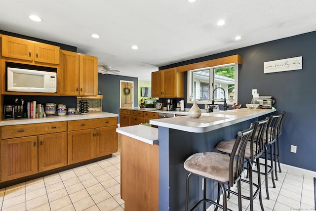 480 Wall St, Hebron, CT 06248 - kitchen featuring white microwave, light countertops, light tile patterned floors, a kitchen bar, and recessed lighting
