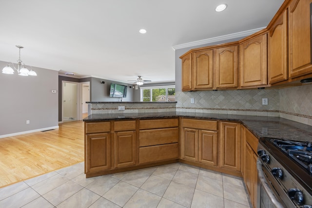 123 Sperry Ln, Meriden, CT 06451 - kitchen with brown cabinets, stainless steel gas range oven, ceiling fan, a peninsula, and backsplash