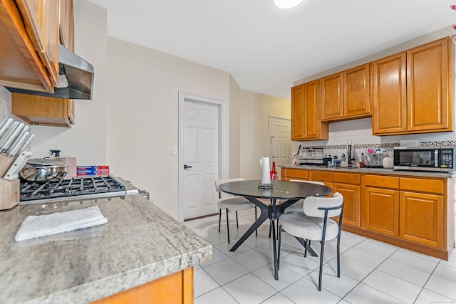 190 Whitney Ave, Bridgeport, CT 06606 - kitchen with stainless steel microwave, tasteful backsplash, light tile patterned floors, and brown cabinetry