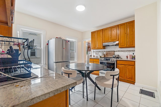 190 Whitney Ave, Bridgeport, CT 06606 - kitchen featuring stainless steel appliances, under cabinet range hood, backsplash, and brown cabinetry