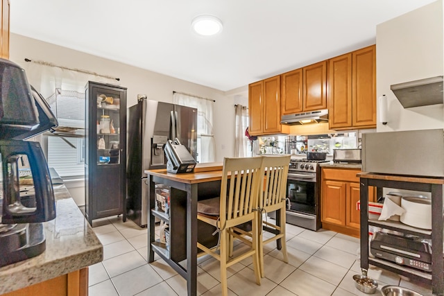 190 Whitney Ave, Bridgeport, CT 06606 - kitchen with appliances with stainless steel finishes, light tile patterned flooring, under cabinet range hood, brown cabinets, and light stone counters