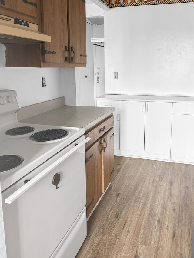 120 Huntington Tpke Unit 606, Bridgeport, CT 06610 - kitchen featuring white range with electric cooktop, under cabinet range hood, light wood finished floors, light countertops, and brown cabinets