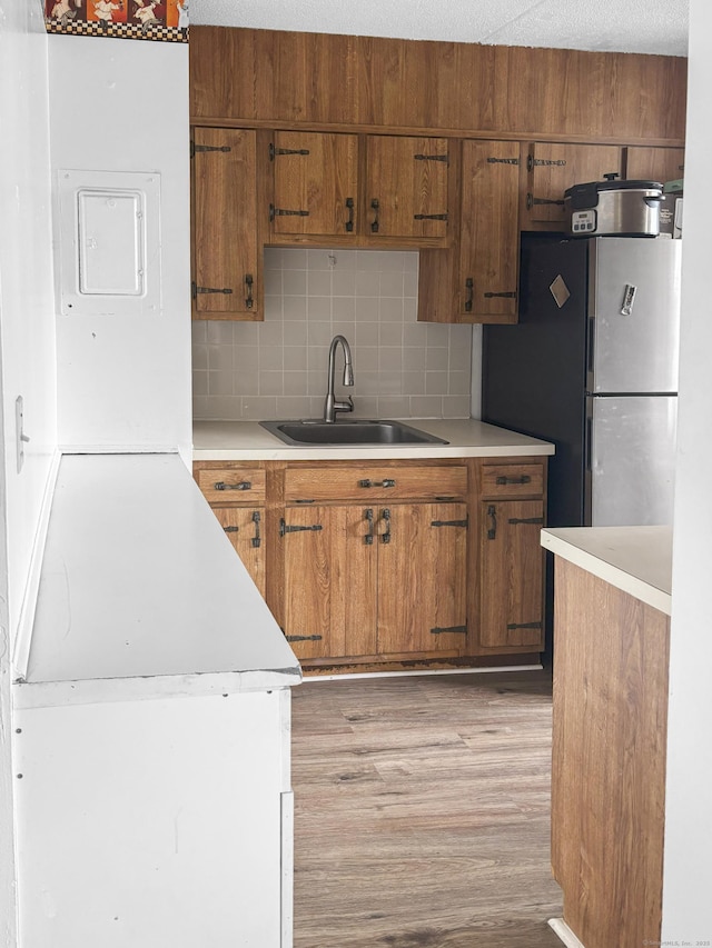 120 Huntington Tpke Unit 606, Bridgeport, CT 06610 - kitchen with freestanding refrigerator, light wood finished floors, brown cabinetry, light countertops, and tasteful backsplash