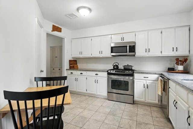 4 Earls Ct Unit 4C, Farmington, CT 06032 - kitchen with appliances with stainless steel finishes, backsplash, light stone counters, and white cabinetry