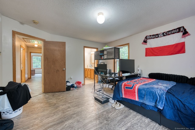 295 Hunting Lodge Rd, Mansfield, CT 06268 - bedroom with light wood-style floors, multiple windows, a textured ceiling, attic access, and connected bathroom