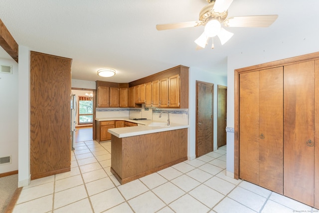 54 Timber Ln, Avon, CT 06001 - kitchen with a peninsula, light countertops, brown cabinetry, black electric stovetop, and freestanding refrigerator