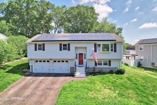 69 Sills Dr, Watertown, CT 06779 - raised ranch with driveway, a front yard, an attached garage, and solar panels