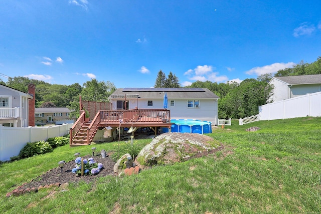 69 Sills Dr, Watertown, CT 06779 - rear view of house featuring a wooden deck, a fenced backyard, roof mounted solar panels, and stairway