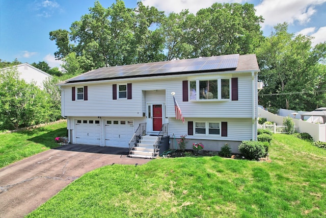 69 Sills Dr, Watertown, CT 06779 - bi-level home with driveway, roof mounted solar panels, and a garage