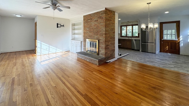 19 Eli Chapman Rd, East Haddam, CT 06469 - unfurnished living room with wood finished floors, ceiling fan, a chandelier, a brick fireplace, and built in features