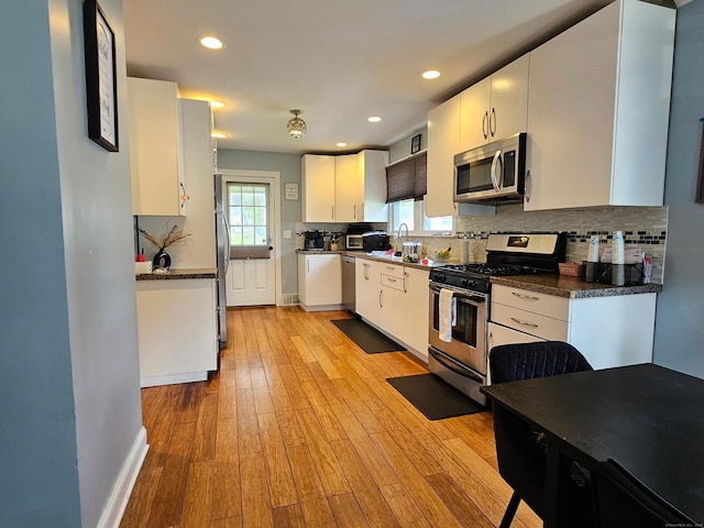 27 White Rose Ave, Waterbury, CT 06708 - kitchen with appliances with stainless steel finishes, backsplash, light wood finished floors, white cabinetry, and recessed lighting