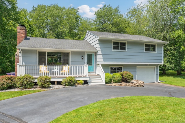 33 Woodside Rd, Guilford, CT 06437 - split level home featuring asphalt driveway, a chimney, a front yard, a garage, and a porch