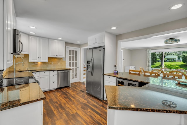 33 Woodside Rd, Guilford, CT 06437 - kitchen featuring appliances with stainless steel finishes, dark wood-style floors, white cabinetry, backsplash, and dark stone countertops