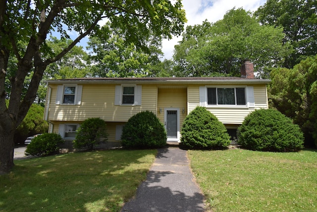 81 Birchwood Dr, Torrington, CT 06790 - raised ranch featuring a front lawn and a chimney