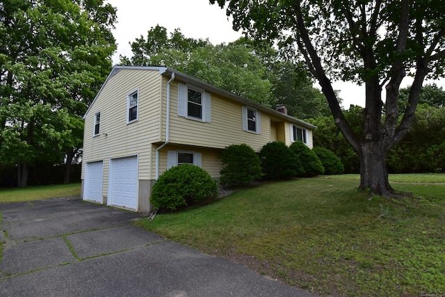 81 Birchwood Dr, Torrington, CT 06790 - view of property exterior featuring a chimney, a garage, driveway, a lawn, and view of wooded area