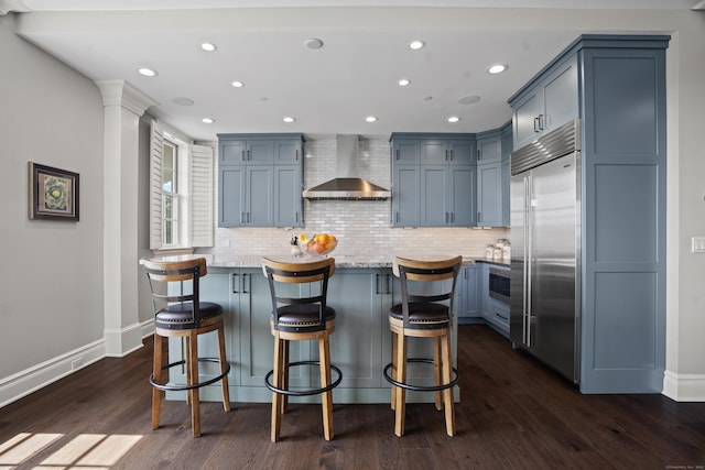 66 High St Unit 31, Guilford, CT 06437 - kitchen featuring wall chimney exhaust hood, stainless steel built in refrigerator, dark wood-style floors, backsplash, and recessed lighting