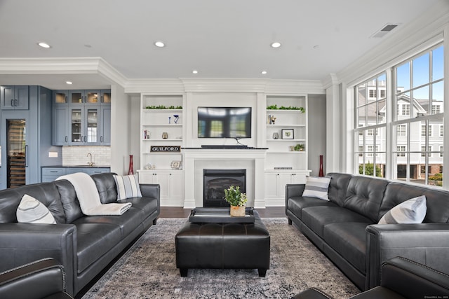 66 High St Unit 31, Guilford, CT 06437 - living area with bar with sink, crown molding, plenty of natural light, a glass covered fireplace, and dark wood finished floors