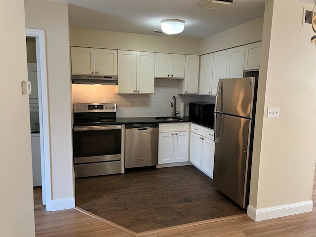 29 Van Buren Ave Unit J4, Norwalk, CT 06850 - kitchen with stainless steel appliances, under cabinet range hood, white cabinetry, dark countertops, and decorative backsplash