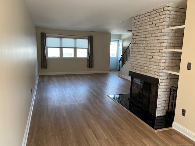 29 Van Buren Ave Unit H7, Norwalk, CT 06850 - unfurnished living room with wood finished floors, a brick fireplace, and stairs