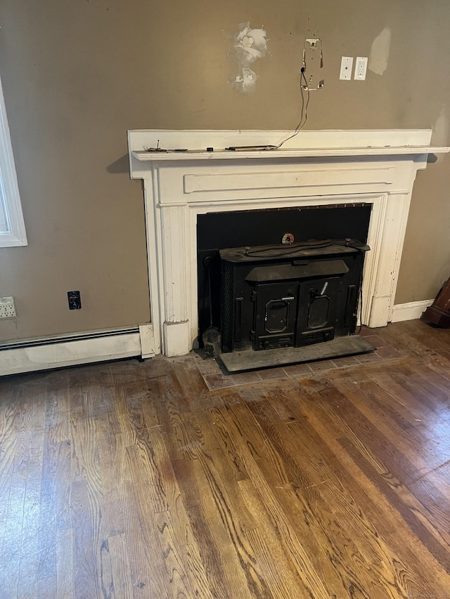 81 Cornwall Dr, Windsor Locks, CT 06096 - detailed view of a wood stove, a baseboard radiator, wood finished floors, and a fireplace