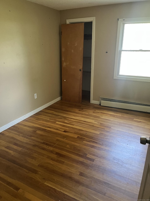 81 Cornwall Dr, Windsor Locks, CT 06096 - unfurnished bedroom featuring a baseboard radiator, dark wood-style floors, a closet, and a spacious closet