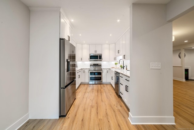 12 Boulevard Dr Unit 27-157, Danbury, CT 06810 - kitchen with stainless steel appliances, light wood-type flooring, tasteful backsplash, light stone countertops, and white cabinets