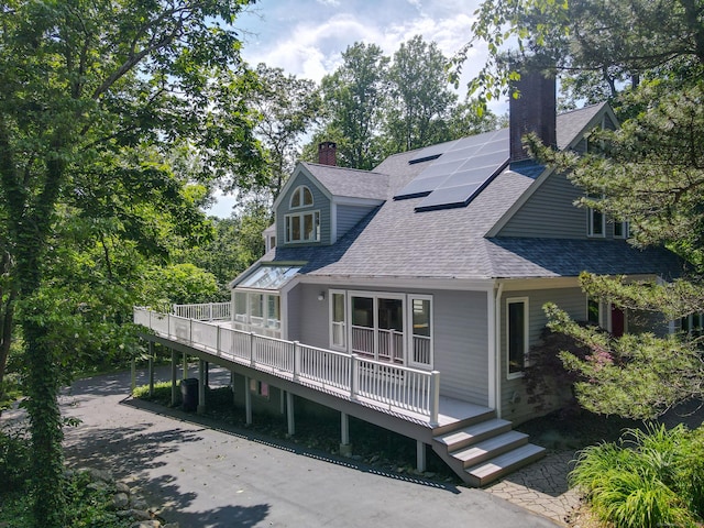 11 Island Bay Cir, Guilford, CT 06437 - back of house with a chimney, roof with shingles, solar panels, and covered porch