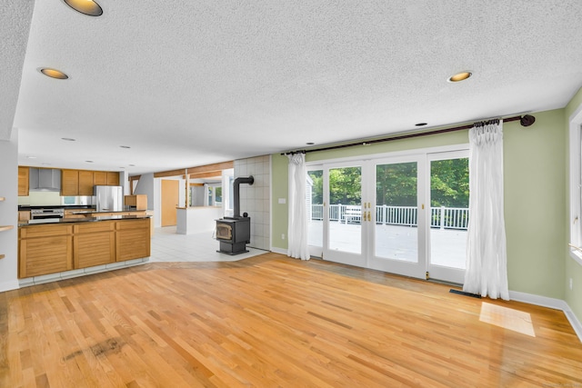 11 Island Bay Cir, Guilford, CT 06437 - unfurnished living room featuring light wood-style flooring, a textured ceiling, a wood stove, recessed lighting, and french doors