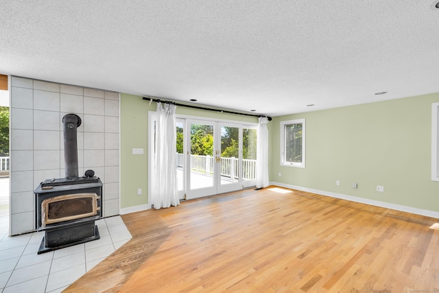 11 Island Bay Cir, Guilford, CT 06437 - unfurnished living room with plenty of natural light, light wood-type flooring, a textured ceiling, and a wood stove