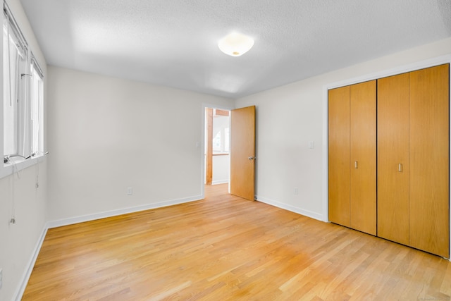11 Island Bay Cir, Guilford, CT 06437 - unfurnished bedroom featuring light wood-style floors, a textured ceiling, and a closet