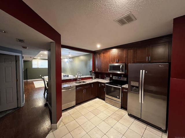 132 Maple Ave Unit B, Hartford, CT 06114 - kitchen featuring appliances with stainless steel finishes, dark brown cabinetry, light stone counters, light tile patterned flooring, and a textured ceiling