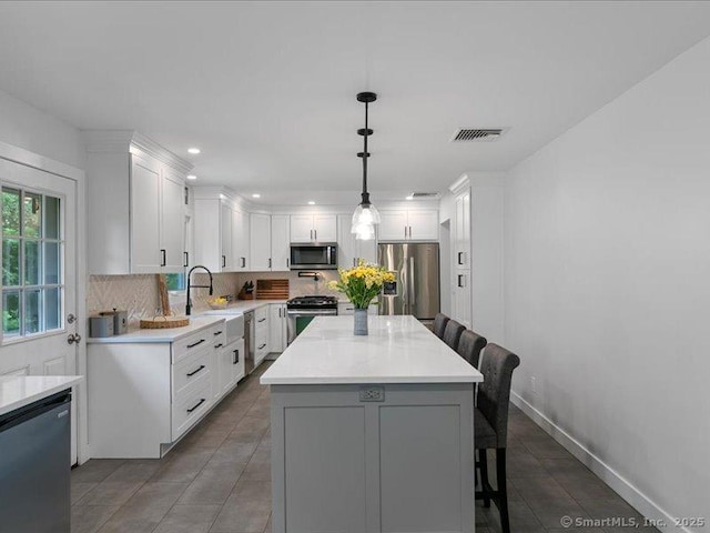 964 Red Fox Rd, Orange, CT 06477 - kitchen with stainless steel appliances, a breakfast bar area, backsplash, light countertops, and white cabinets