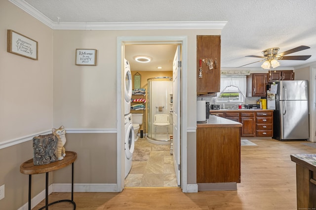 141 Peach Orchard Rd, Waterbury, CT 06706 - kitchen featuring freestanding refrigerator, stacked washer / drying machine, ornamental molding, ceiling fan, and a textured ceiling